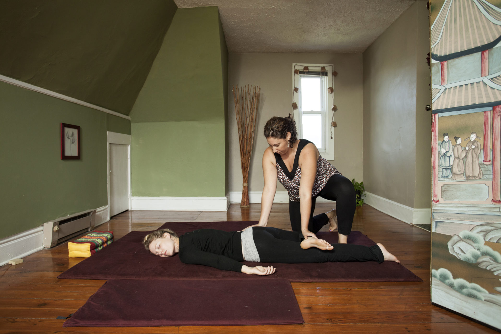 Sarah Becker giving Thai massage, patient on floor